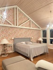 - une chambre avec un lit dans une pièce ornée de papier peint floral dans l'établissement Grand Hideout Lake Päijänne, à Vääksy