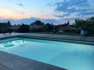 einen Pool mit Sonnenuntergang im Hintergrund in der Unterkunft La Grange aux hirondelles - appartement complet et indépendant in Commelle-Vernay