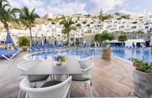 波多黎各的住宿－Bahia & Ocean Views - Holiday Club Deluxe Private Suite，度假村游泳池旁的桌椅