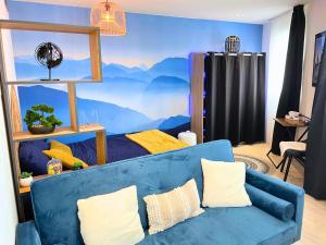 un salon avec un canapé bleu et une fresque murale de montagne dans l'établissement [L’Écrin] Studio equipé avec vue panoramique, à Lourdes
