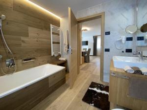 a bathroom with a tub and a sink at Ciasa Nene Franzl in Badia