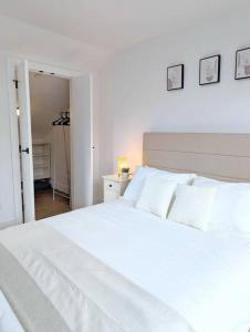 een wit bed met witte kussens in een slaapkamer bij Centrally located, modern, 2 bedroom home in Vancouver