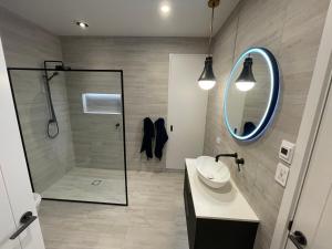 a bathroom with a shower and a sink and a mirror at Guesthouse @ Te Puna in Tauranga