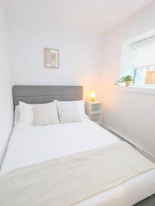 a white bed in a white bedroom with a window at Centrally located, modern, 2 bedroom home in Vancouver
