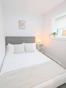 een wit bed in een witte slaapkamer met een raam bij Centrally located, modern, 2 bedroom home in Vancouver