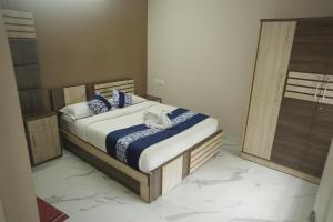 a bedroom with a bed with blue and white sheets at Luxe Hotel - Rooms & Villas Wayanad in Wayanad