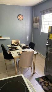 a dining room table with chairs and a clock on the wall at 1 Cozy Bedroom Apartment in Kingston