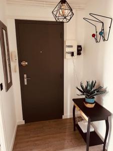 un couloir avec une porte noire et une table avec une plante dans l'établissement Cocon berrichon Châteauroux-Déols, à Déols