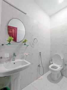W łazience znajduje się umywalka, toaleta i lustro. w obiekcie Holidazzle Lodge Islamabad w mieście Islamabad