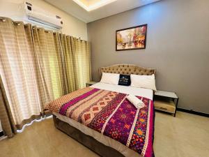 a bedroom with a bed with a colorful blanket at Holidazzle Lodge Islamabad in Islamabad