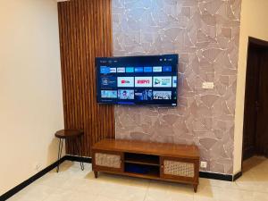 TV de pantalla plana colgada en la pared en Holidazzle Lodge Islamabad en Islamabad