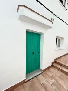 - une porte verte dans un bâtiment blanc avec des escaliers dans l'établissement Casa Abuela Ana, à Alcalá de los Gazules