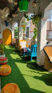 Manavi Hostel Near by Mathura Railway Station في ماثورا: غرفة بها عشب أخضر وكراسي على الفناء
