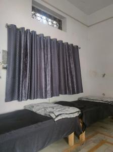 two beds in a room with black curtains at Manavi Hostel Near by Mathura Railway Station in Mathura