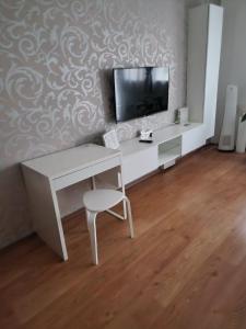 a white desk with a tv and a chair in a room at Orchidea Apartman in Gödöllő