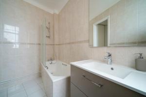 a bathroom with a sink and a tub and a mirror at Appartement Arc de Triomphe - Neuilly - II in Neuilly-sur-Seine