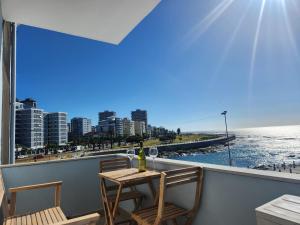 a table and chairs on a balcony with a view of the ocean at Sunset Retreat at Bay Point in Cape Town