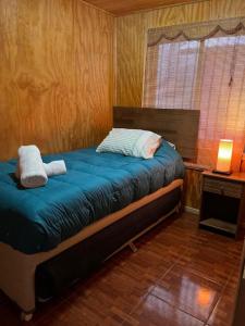 Cabañas Rukaparra في Pinto: غرفة نوم بسرير وملاءات زرقاء ونافذة