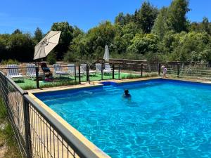 Cabañas Rukaparra في Pinto: مسبح فيه شخص في الماء