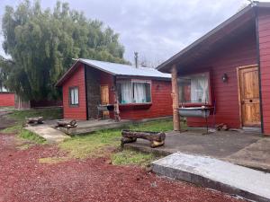 ein rotes Haus mit Holzscheiten davor in der Unterkunft Cabañas Rukaparra in Pinto