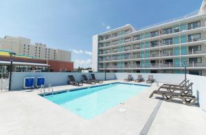 a swimming pool with chairs and a building at Howard Johnson by Wyndham Virginia Beach At The Beach in Virginia Beach