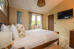 a bedroom with a large white bed with a window at Hideaway Lodge in Tintagel