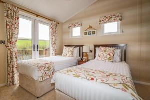 two beds in a room with two windows at Hideaway Lodge in Tintagel