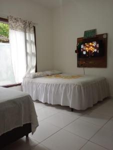 2 Betten in einem Zimmer mit einem TV an der Wand in der Unterkunft Casa da Praia da Adriana in Ubatuba