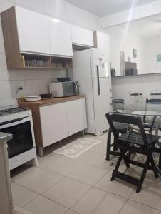 eine Küche mit weißen Schränken und einem Tisch mit einem Stuhl in der Unterkunft Casa da Praia da Adriana in Ubatuba
