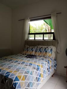 Bett in einem Zimmer mit Fenster und Tagesdecke in der Unterkunft Casa da Praia da Adriana in Ubatuba