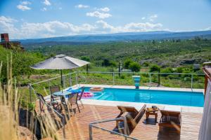 uma piscina com uma mesa e cadeiras e um guarda-sol em Casa Altiva em Estancia Vieja