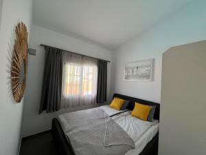 a bedroom with a bed with yellow pillows and a window at Aloha Apartman Arguineguin in Arguineguín +22 photos
