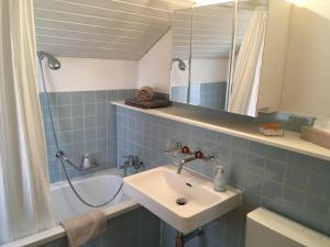bagno piastrellato blu con lavandino e doccia di B3 Apartment a Gsteigwiler