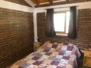 a brick walled bedroom with a bed and a window at Brisa del Bosque in El Bolsón