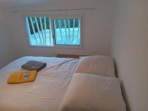 Cama blanca en habitación con ventana en Le Jardin, en Saint-Leu