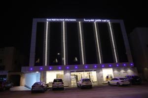 un edificio con auto parcheggiate di fronte ad esso di notte di روز نجد للشقق الفندقية a Riyad