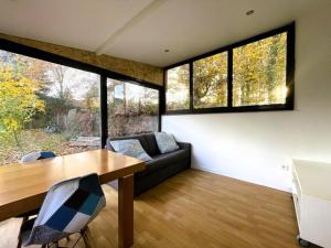 een woonkamer met een tafel, een bank en ramen bij Charmante maison avec extérieur in La Queue-en-Brie
