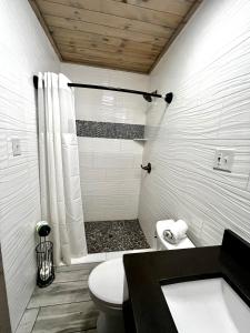 a white bathroom with a shower and a toilet at Gulf Coast Inn in Gulf Breeze