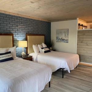 a bedroom with two beds and a brick wall at Gulf Coast Inn in Gulf Breeze