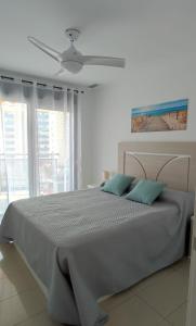 a white bedroom with a large bed with blue pillows at Apartamento Vistas al mar en Gemelos 24 La Cala de Finestrat in Alicante