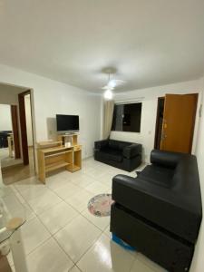 ein Wohnzimmer mit einem schwarzen Sofa und einem TV in der Unterkunft Apartamento no Ilha Bela 2 in Caldas Novas