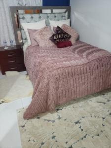 uma cama com um cobertor rosa e almofadas em cabaña mariposa monarca em Mineral de Angangueo