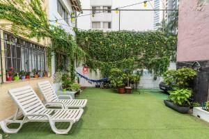 a patio with two white chairs and plants at Casa Charmosa de Vila - Lapa in Sao Paulo