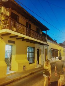 Un uomo e una donna che passano davanti a un edificio giallo di Habitaciones Ciudad Amurallada a Cartagena de Indias