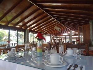 une salle à manger avec une table, des assiettes et des verres dans l'établissement Pousada Sonho de Geribá, à Búzios