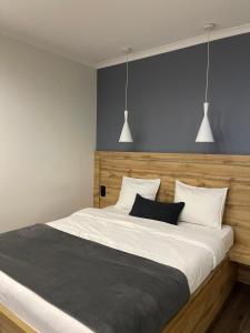 a bedroom with a large bed with two pendant lights at SCANDIC apartments-feels like home! in Lviv