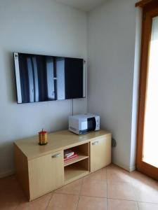 a living room with a tv and a cabinet with a microwave at Appartamento Torrefranca in Trento