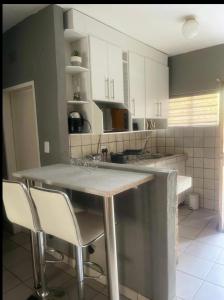 a kitchen with white cabinets and a island with chairs at Kganya@Sunset Lodge in Phalaborwa