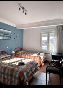 two beds in a room with blue walls and windows at Vista a la montaña Briviesca in Briviesca