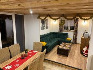 a living room with a green couch and a table at Jaśkowa Chata Bieszczady apartament z basenem in Baligród